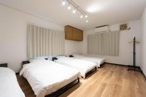 three beds in a room with white walls and wooden floors at Shima Yadori Ao in Oshima