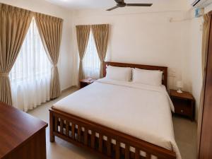 a bedroom with a large bed and two windows at Serene Padmanabham Premium Luxury Apartments Near Sree Padmanabhaswamy Temple in Trivandrum
