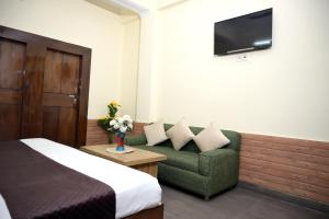 a hotel room with a bed and a couch and a tv at Hotel King By Panch Aarohan in Pithorāgarh