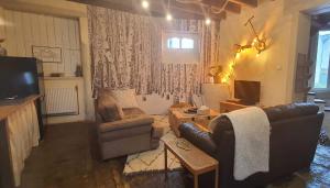 a living room with a leather couch and a television at Le Figuier , Domaine La Capitainerie in Bazoges-en-Pareds