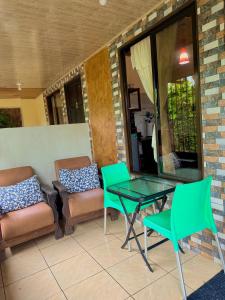 a patio with green chairs and a glass table at Cabinas Arenal Z-13 in Fortuna