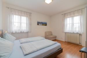 a bedroom with a bed and two windows at Stompferhof Erkerwohnung in Caldaro