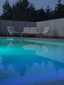 two chairs and a swimming pool with blue water at Apartamenty Nadmorska Osada in Łeba