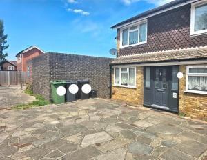 a brick house with two trash cans in front of it at Orpington North Townhouse in Orpington