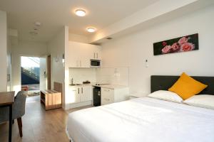 a bedroom with a white bed and a kitchen at Yates Park Motel in Auckland