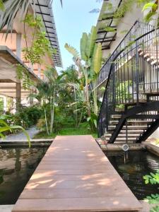 a wooden walkway over a pond in a building at Phan NaTa Residence in Siem Reap