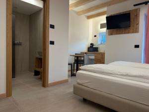 a bedroom with a bed and a tv on the wall at Liz Hotel & Apartments in Predazzo