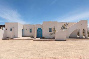 a white building with a blue door and a staircase at Dar Ahlem Djerba in El Guecheïne