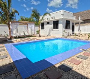 a swimming pool in front of a house at Cappuccinovilla in Paje