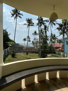 a balcony with a view of palm trees and the ocean at hello varkala beach view balcony resort in Varkala