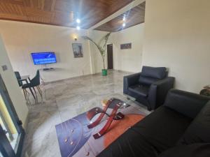a living room with a couch and chairs and a tv at NS Immo Yaounde Cameroun in Yaoundé
