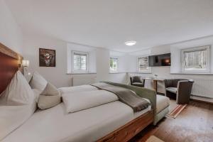a white bedroom with a bed and a living room at Landhaus Waldesruh in Oetz