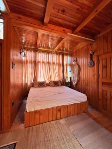 a bedroom with a bed in a room with wooden walls at Cedar Forest BnB Villa in Kasol