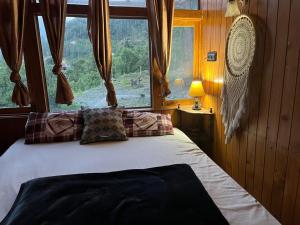 a bedroom with a bed with a large window at Cedar Forest BnB Villa in Kasol