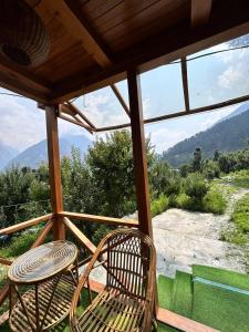 a porch with a chair and a table and a view at Cedar Forest BnB Villa in Kasol