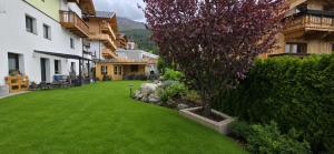 a green yard with a tree in front of a house at Haus Alpenpanorama in Fendels