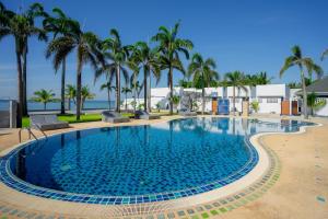 a large swimming pool with palm trees in the background at เจ้าหลาว ซี บรีส รีสอร์ท in Ban Mu Dut
