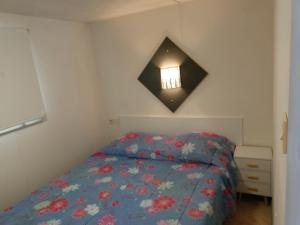 a bedroom with a bed with a blue comforter and a window at Thery location 17 in Saint-Pierre-dʼOléron