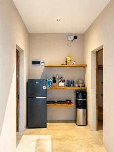 a kitchen with a black refrigerator and a shelf at Villa Marieta - Two Bedrooms Private Villa in Kuta Lombok