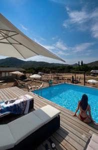a woman sitting on a deck next to a swimming pool at Les Chalets De Tesa 4 in Occhiatana