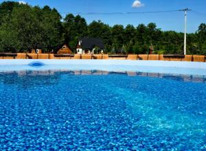 a pool of blue water with a house in the background at Casa Del Campo 1 in Gaśno