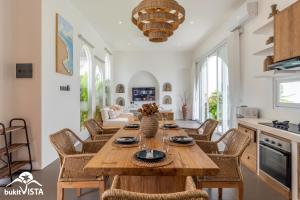a kitchen and living room with a wooden table and chairs at Villa Luminosa 3 by Bukit Vista in Uluwatu