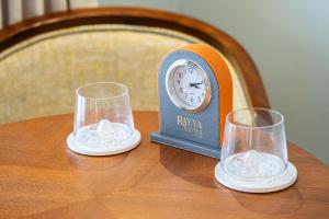 a clock sitting on top of a table with two glasses at Rayya Suites , Invercargill in Invercargill