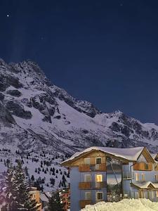 a ski lodge with a snow covered mountain in the background at Hotel Cielo Blu in Passo del Tonale