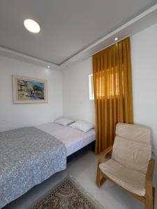 a bedroom with two beds and a chair and a window at Vengo Apartments in Kotor
