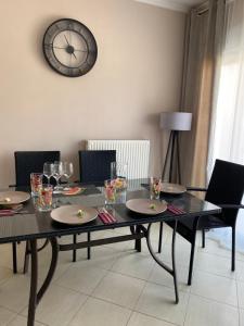 a dining room table with chairs and a clock on the wall at Potamos Townhouse & Shared Garden in Potamós