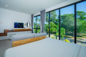 a bedroom with a bed and large windows at เจ้าหลาว ซี บรีส รีสอร์ท in Ban Mu Dut