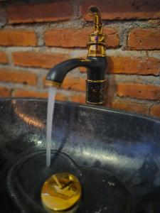 a sink with a faucet with water coming out at pesisircottage & stay in Selong Belanak
