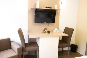Habitación con escritorio con 2 sillas y TV. en Grand Central Accommodation - Smardan, en Bucarest