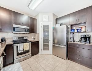 a kitchen with stainless steel appliances and brown cabinets at Rome, Sweet Home in Calgary