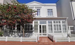 a white house with a white fence and a tree at Buten un Binnen in Norderney