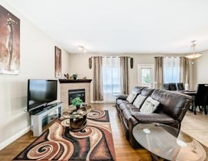 a living room with a leather couch and a television at Rome, Sweet Home in Calgary