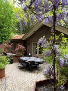 a patio with a table and chairs in front of a house at Berg en Bos Suite met luxe jacuzzi in Apeldoorn