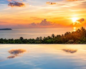 a pool of water with a sunset in the background at INDIGO VILLA Samui in Koh Samui +64 photos