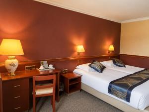 a hotel room with two beds and a desk at Ambassador Hotel Eupen in Eupen