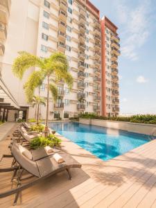 a swimming pool with lounge chairs and a building at Elegant 1BR Unit at Bryant Parklane, Capital Town near Malls and Tourist Destinations in Pampanga, Free Pool Access, Netflix, Prime Video in San Fernando +13 photos