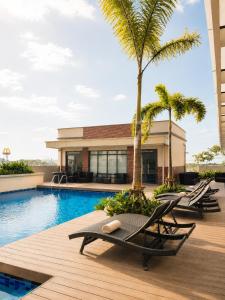 a resort pool with lounge chairs and palm trees at Elegant 1BR Unit at Bryant Parklane, Capital Town near Malls and Tourist Destinations in Pampanga, Free Pool Access, Netflix, Prime Video in San Fernando