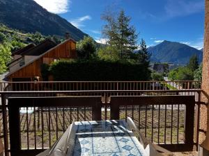 a balcony with a table and a fence and mountains at Chaleureux appartement moderne in Briançon +2 photos