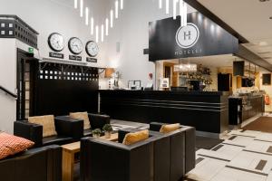 a restaurant with couches and clocks on the wall at Hotel Aateli Lakeside in Vuokatti +21 photos