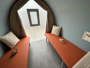 two orange benches in a room with a window at Camping Du Lion in Bourg-Saint-Andéol