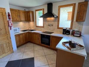 een keuken met houten kasten en een kookplaat met oven bij NEW Chalet Le Sabot 12p - Sauna - 90m telecabine in Oz