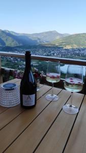 a bottle of wine and two glasses on a wooden table at Sunčani Brijeg Eco Village in Plav