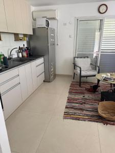 a kitchen with a refrigerator and a table and a chair at Hamsa Apartment in Menaẖemya