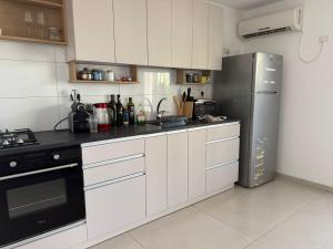 a kitchen with white cabinets and a stainless steel refrigerator at Hamsa Apartment in Menaẖemya