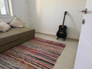 a room with a couch and a guitar next to a rug at Hamsa Apartment in Menaẖemya