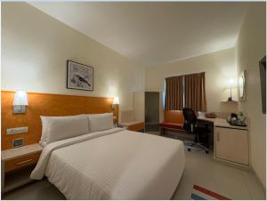 a hotel room with a large bed and a desk at Aditya Hometel in Hyderabad +18 photos